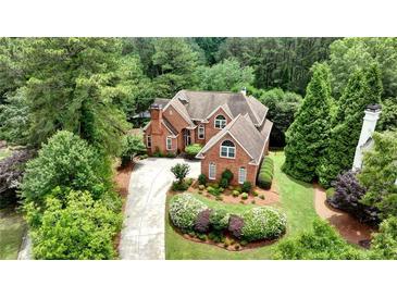 Aerial view of a red brick home with a large yard and mature trees providing a private, secluded feel at 119 Kennemer Ct, Johns Creek, GA 30097