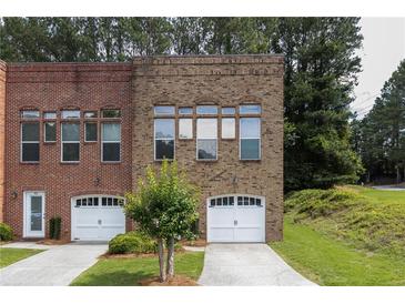 Brick townhome exterior with garage, front yard, and beautiful, timeless architectural details at 90 Grove Park Ln, Woodstock, GA 30189