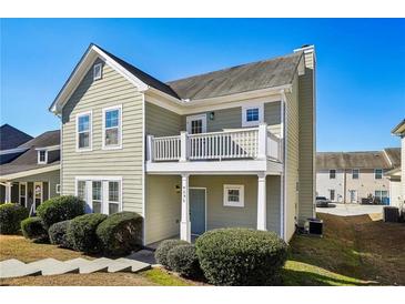 Charming two-story home with a balcony, light green siding, a well-manicured lawn and a blue front door at 4593 Parkway Cir, Atlanta, GA 30349