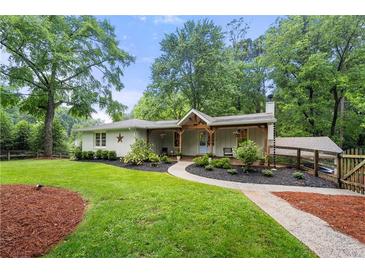 Charming one-story home with a landscaped yard, wooden porch, and a welcoming entrance surrounded by lush greenery at 2020 New Kemp Rd, Marietta, GA 30066