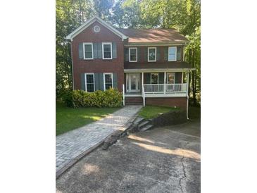 Charming two-story brick home with a covered front porch and neatly landscaped yard and a stone-paved driveway at 1970 Sturbridge Ln, Buford, GA 30519