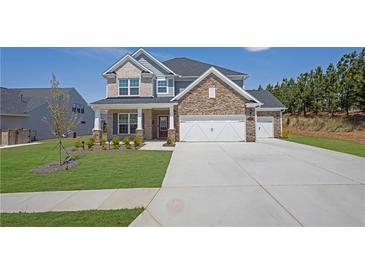 Two story home with mixed stone and vinyl siding, manicured lawn and 3-car garage at 307 Ernest Ave, Peachtree City, GA 30269