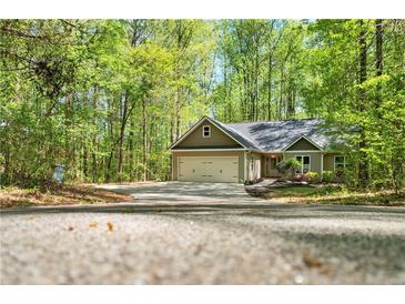 Charming home with a two-car garage and a large driveway surrounded by lush trees at 191 Orchard Dr, Canton, GA 30115