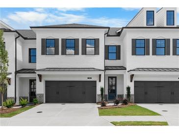 Charming townhome showcases a light brick facade, black trim, garage, and manicured lawn at 709 Dodd Ln # 165, Buford, GA 30518