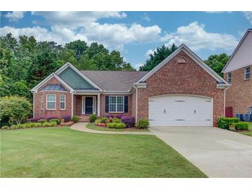 Charming brick home with manicured lawn, colorful flowerbeds, and a two-car garage at 4235 Crestwood Bend Cir, Buford, GA 30518