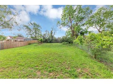 Spacious backyard features lush green grass and chain link fence with shade trees along the border at 1338 Georgia Ave, Atlanta, GA 30344