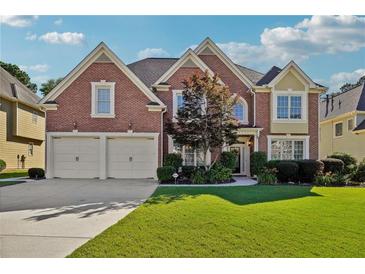 Charming brick home featuring a well-manicured lawn and a two-car garage, set under a bright, partly cloudy sky at 2909 Everson Ridge Ct, Snellville, GA 30039