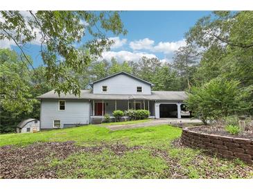 Charming home featuring a covered front porch, attached garage, and beautifully landscaped front yard at 8464 Pleasant Hill Rd, Lithonia, GA 30058