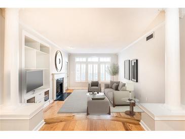 Bright living room with fireplace, built-in shelving, hardwood floors, and large windows at 220 Renaissance Ne Pkwy # 1105, Atlanta, GA 30308