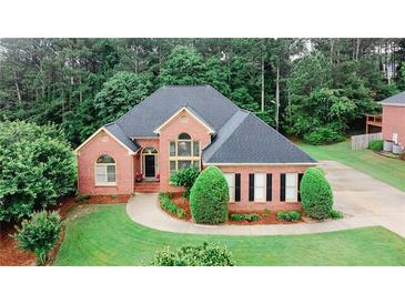 Beautiful brick home with manicured lawn, professional landscaping, and mature trees offering curb appeal at 8108 Greens Mill Way, Loganville, GA 30052