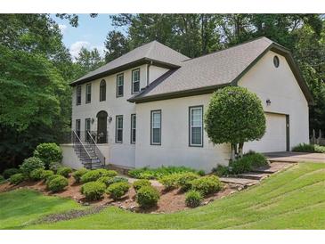 Elegant two-story home with manicured lawn and lush landscaping, steps lead to arched entry at 2819 Saddlebrook Nw Way, Marietta, GA 30064