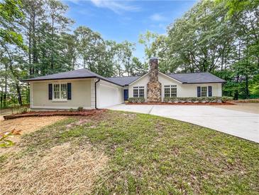 Charming single-story home featuring a stone chimney, driveway, and manicured lawn at 2734 Amber Springs Way, Buford, GA 30519