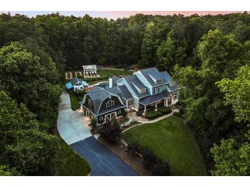 Stunning aerial view of estate home nestled among mature trees with detached garage and greenhouse at 390 Hembree Rd, Roswell, GA 30075