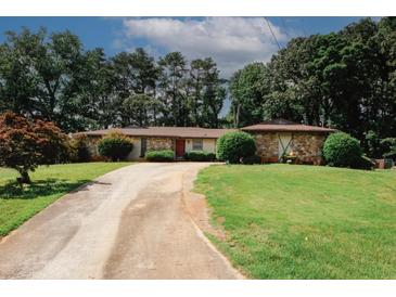 Charming single-story home with stone accents, lush lawn, and a long driveway at 3257 Georgian Woods Cir, Decatur, GA 30034