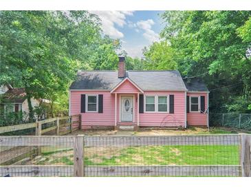 Charming pink cottage-style home with black shutters and a well-maintained front yard surrounded by mature trees at 207 Walthall Nw St, Marietta, GA 30064