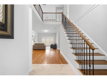 Bright foyer featuring hardwood floors, staircase with iron railings, and an open view to the living area at 3280 Stillhouse Se Ln # 410, Atlanta, GA 30339