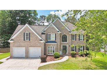 Charming brick two-story home with manicured lawn, two-car garage, and mature landscaping at 445 Sweet Ivy Ln, Lawrenceville, GA 30043