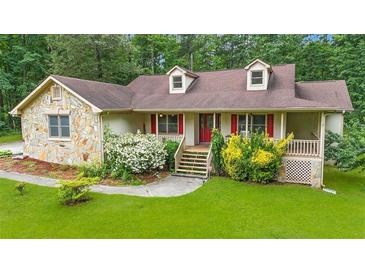 Charming home featuring a stone facade, dormer windows, a well-manicured lawn and abundant landscaping at 3488 Pebble Brook Ln, Stockbridge, GA 30281