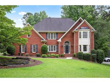 Charming two-story red brick home featuring manicured lawn, mature trees, and classic architectural details at 963 Bolingbrook Sw Dr, Marietta, GA 30064