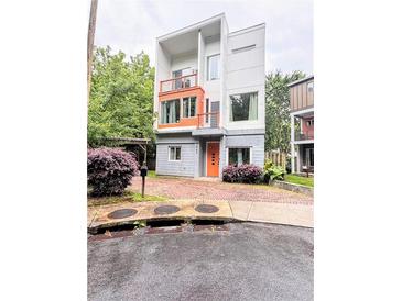 Modern three-story home featuring a unique architectural design with a bright orange door and matching balcony accents at 1463 Macklone Ne St, Atlanta, GA 30307