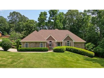 Charming single-story home featuring a combination of stone and tan siding, complemented by lush landscaping at 115 Windover Ct, Roswell, GA 30075