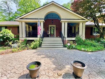 Charming brick home with a covered porch, manicured landscaping, and a patterned concrete driveway at 431 Keeler Woods Nw Dr, Marietta, GA 30064