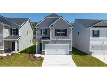 Charming two-story home features gray siding, a front-entry garage, and a well-maintained lawn at 12086 Conrad Cir, Hampton, GA 30228