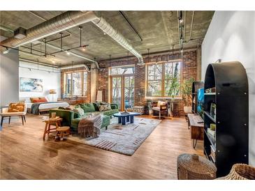Spacious living room featuring hardwood floors, exposed brick, and large windows providing natural light and city views at 3235 Roswell Ne Rd # 508, Atlanta, GA 30305