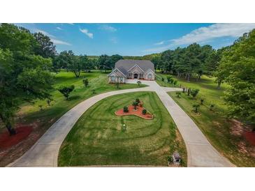 Expansive front yard with a circular driveway leading to a beautiful brick home, surrounded by mature trees and lush landscaping at 100 Marshas Vineyard, Hampton, GA 30228