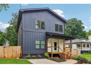 Charming two-story home with vertical siding, a covered porch, and manicured landscaping at 1129 Victory Sw Dr, Atlanta, GA 30310
