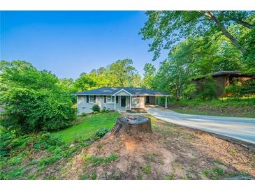 Charming single-story home with a covered parking, inviting curb appeal and lush green surroundings at 4457 Lincoln Jones Rd, Ellenwood, GA 30294