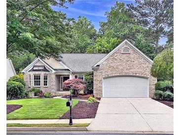 Charming brick home featuring an attached garage, well-manicured lawn, and beautiful landscaping at 554 Grand Ashbury Ln, Sugar Hill, GA 30518
