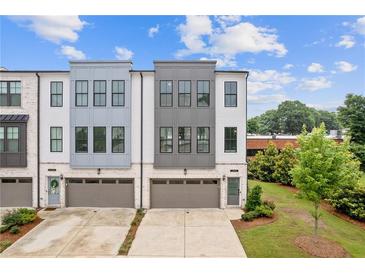Modern townhome with a mix of white and gray exterior paint, gray brick accents, and a two car garage at 2808 Maddison Towns Ave, Norcross, GA 30071
