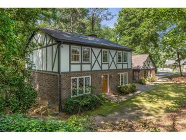 Charming two-story Tudor home featuring a brick facade and decorative wood trim surrounded by mature trees at 965 Heards Ferry Rd, Sandy Springs, GA 30328