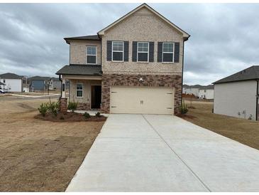 Two-story home featuring a two-car garage and a mix of brick and siding on the facade at 1001 Limburg Dr, Hampton, GA 30228