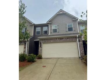 Two story townhome with a large garage, concrete driveway and neutral colored brick and siding at 2778 Wild Laurel Ct, Norcross, GA 30071