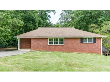 Charming brick home featuring manicured lawn, windows and mature trees at 256 Indian Trl, Marietta, GA 30068