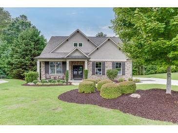 Charming brick home with well-manicured lawn, mature trees, and inviting front porch with outdoor seating at 7070 Concord Mountain Trl, Cumming, GA 30028
