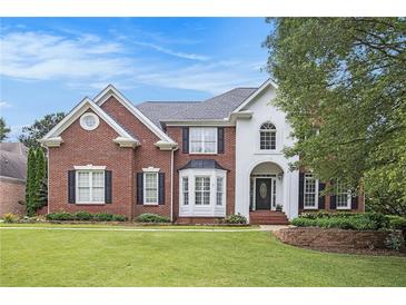 Beautiful brick and stucco home featuring a manicured lawn and classic architectural details at 650 Garden Wilde Place, Roswell, GA 30075