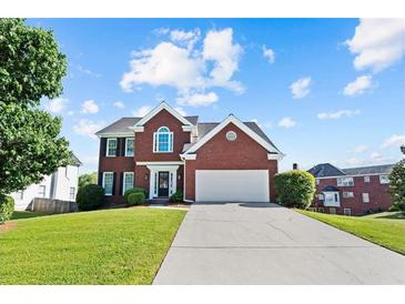 Charming two-story red brick home with a two-car garage and well-manicured lawn on a beautiful day at 3226 Masters Pass Ln, Snellville, GA 30039