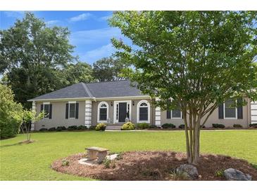 Charming single story home with well maintained lawn, mature trees and appealing stone bench at 2265 Colony Dr, Canton, GA 30114
