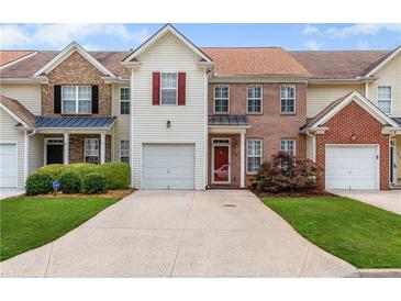 Charming townhome featuring a one car garage, red front door, manicured lawn, and inviting curb appeal at 2924 Greyhawk Ln, Cumming, GA 30040