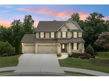 Charming two-story brick home with a three-car garage and landscaped front yard at sunset at 2330 Cheatham Creek Ct, Cumming, GA 30040