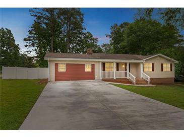 Charming one-story home with red accents, an attached garage, mature trees and a spacious concrete driveway at 25 Carriage Ct, Stockbridge, GA 30281