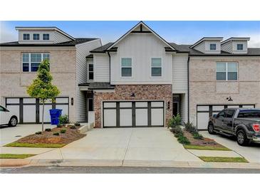 Charming townhome featuring a two-car garage, brick accents, and well-maintained landscaping at 94 Depot Landing Rd, Auburn, GA 30011