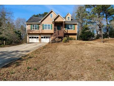 Two-story home with a two-car garage, and a wooden staircase leading to the front door at 120 Paces Lakes Pt, Dallas, GA 30157