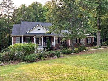 Charming single-story brick home features a covered front porch and lush landscaping at 19 Thimblemill Ct, Villa Rica, GA 30180