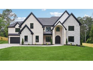 Striking white brick home featuring black accents, a manicured lawn, and professional landscaping at 4539 Braselton Hwy, Hoschton, GA 30548