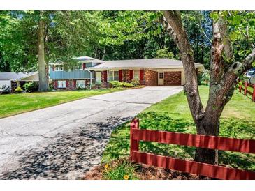 Charming home featuring a long driveway and inviting curb appeal with mature trees and red shutters at 5152 Suggs St, Powder Springs, GA 30127