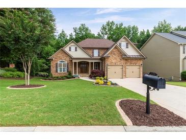 Charming two-story home featuring a stone facade, well-manicured lawn, and a two-car garage at 2430 Hemrick Rd, Cumming, GA 30041